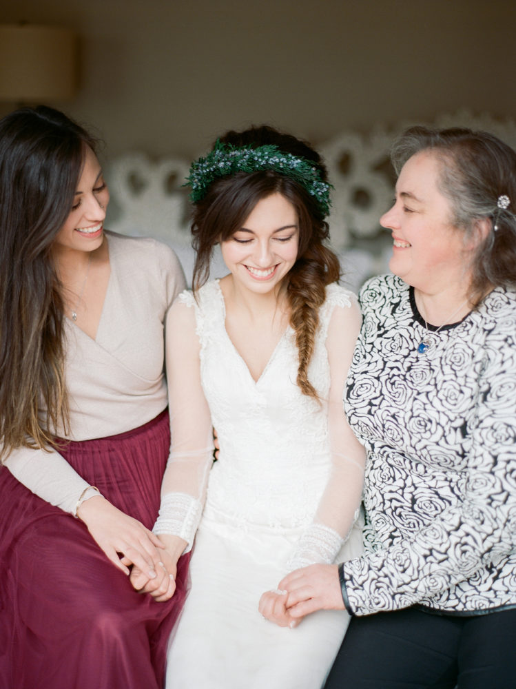 bride sister and mother sitting on bed